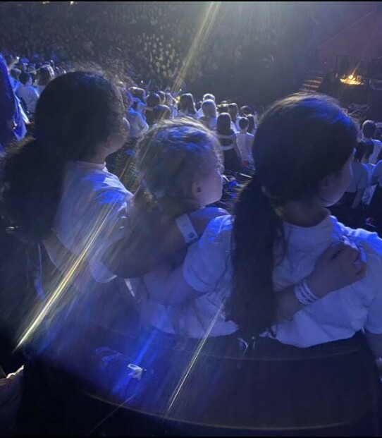 Children pictured with their arms around eachother, performing at AO Arena